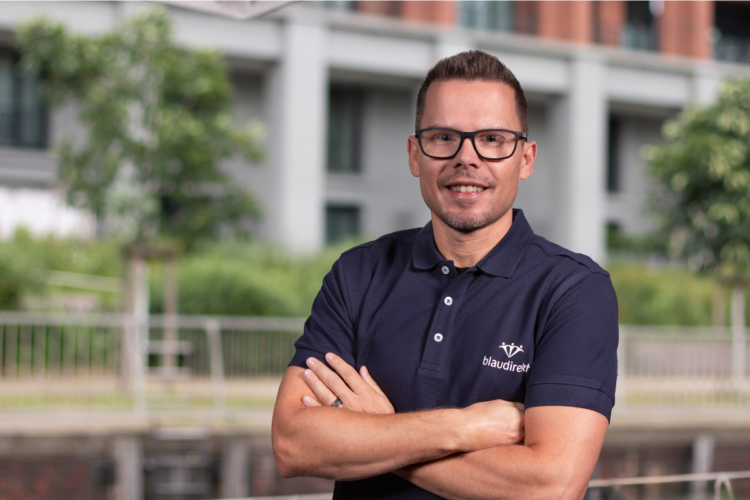 Mann mit verschränkten Armen lächelt in die Kamera