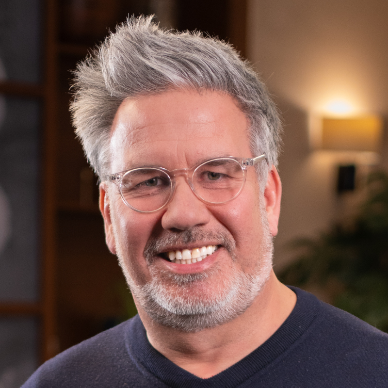 Ein lächelnder Mann mit Bart und Brille.