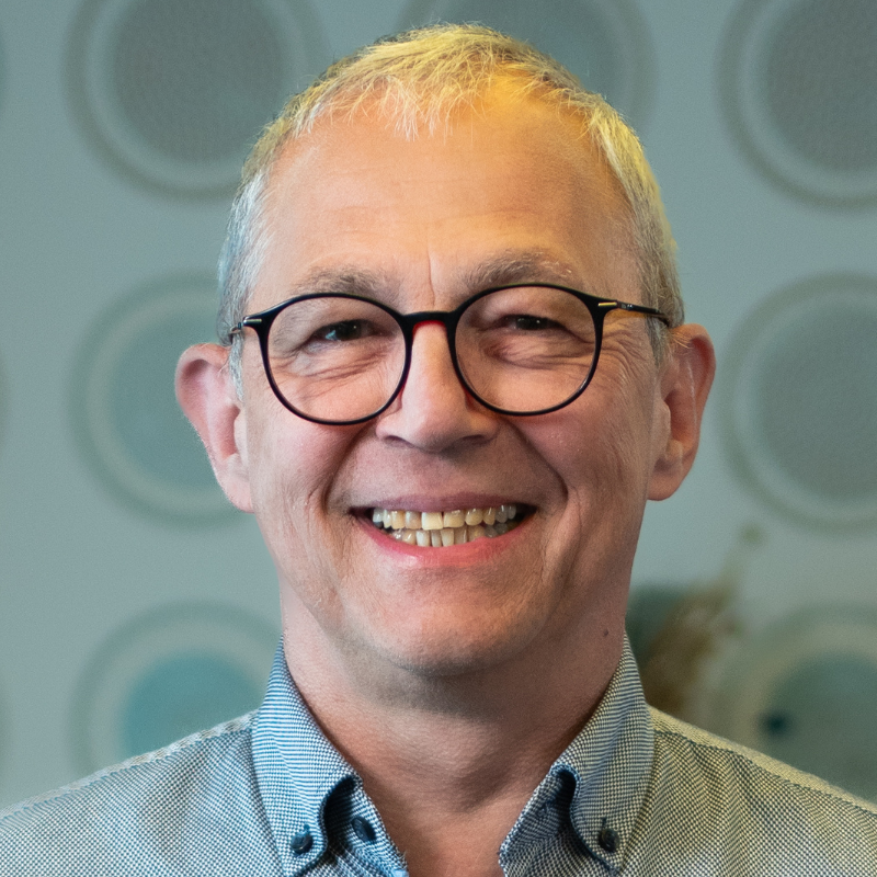 Ein lächelnder Mann mit Brille und Hemd.