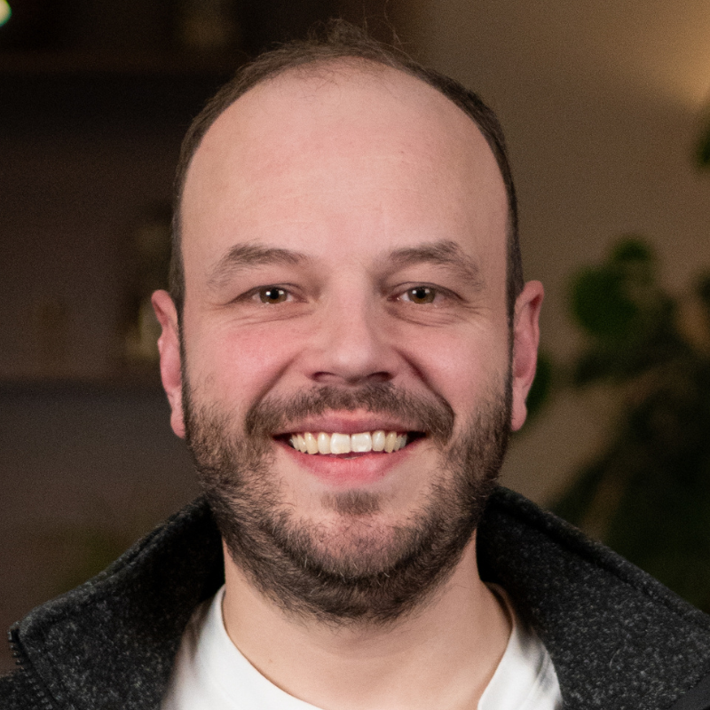 Ein lächelnder Mann mit Bart.