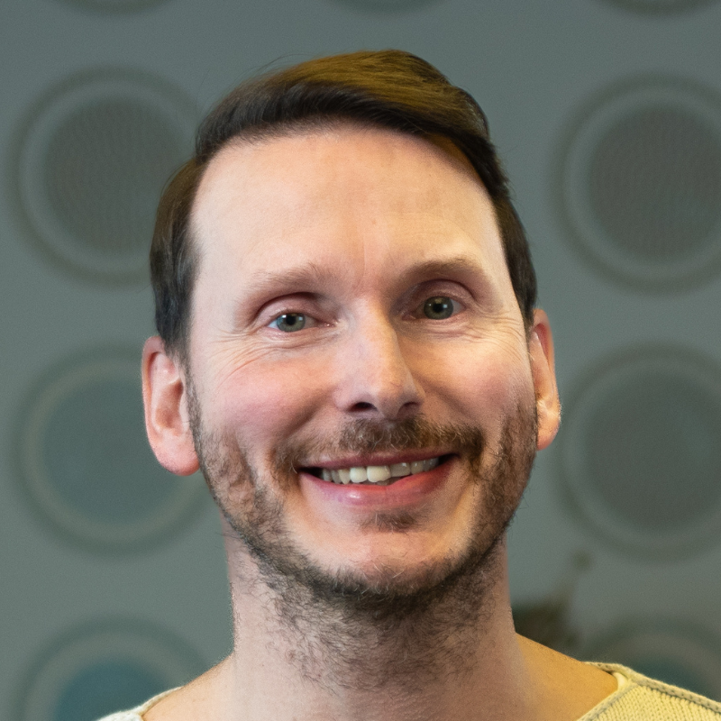 Ein lächelnder Mann mit Bart.