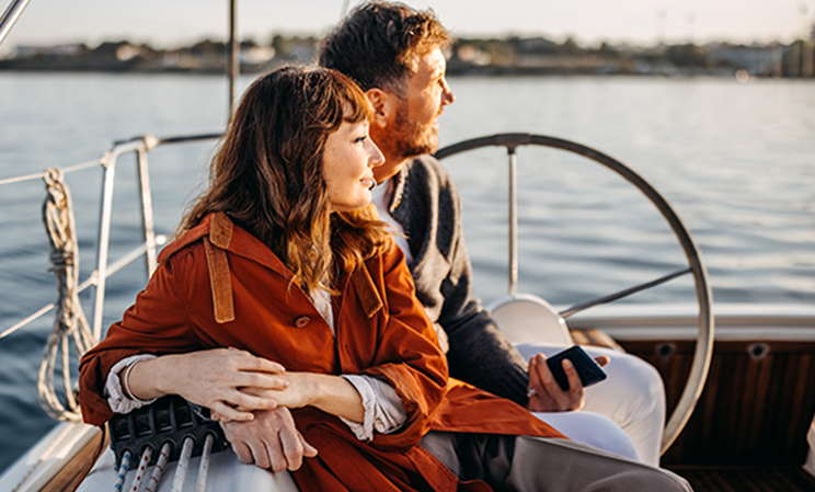 Zwei Personen auf Segelschiff, Arm in Arm Blicken Richtung Sonne