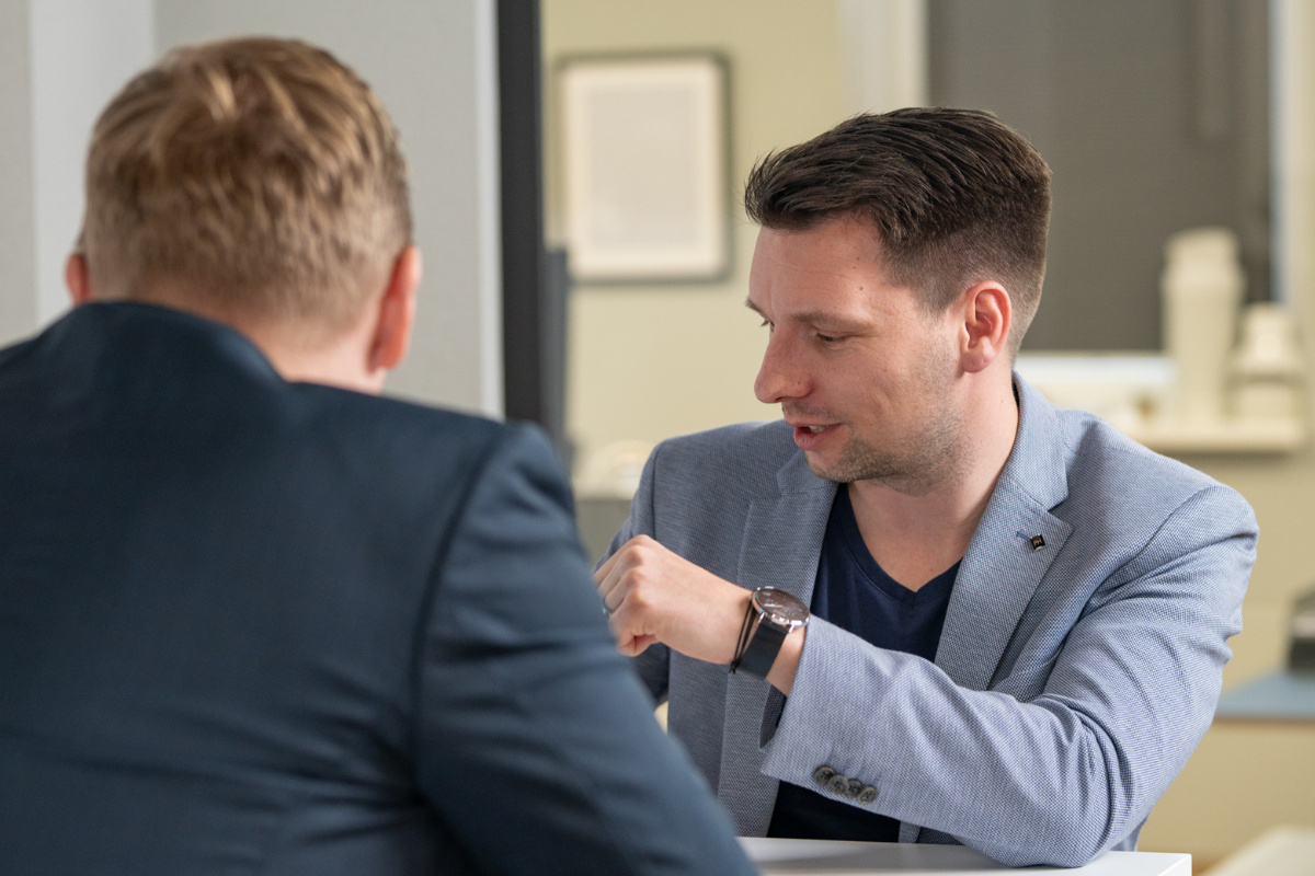 Zwei Männer im Anzug sitzen sich bei einem Gespräch an einem Tisch gegenüber